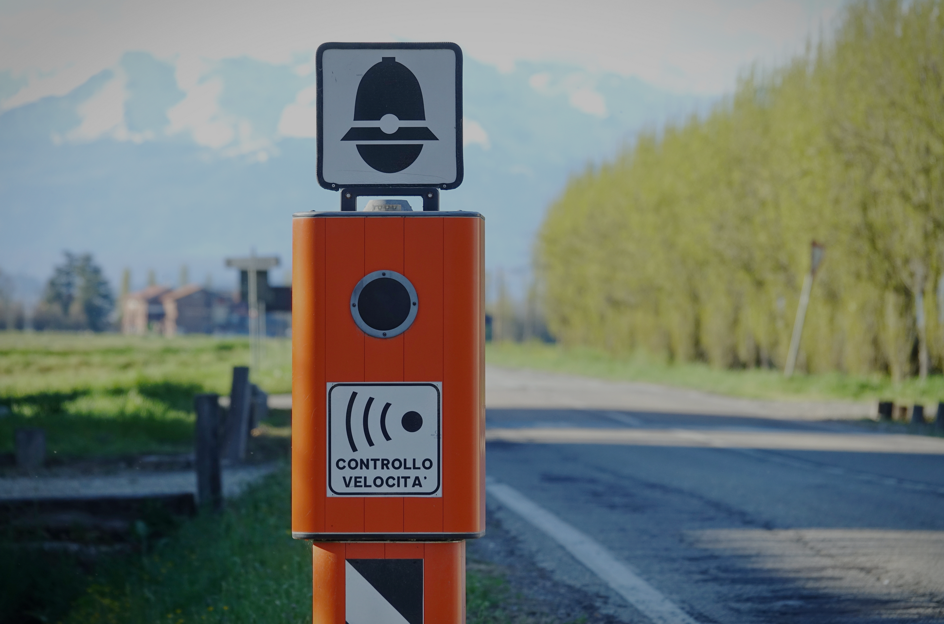 Autovelox arancione con cartello Controllo Velocità su strada rurale, posizione ideale per l'utilizzo di un rilevatore di autovelox.